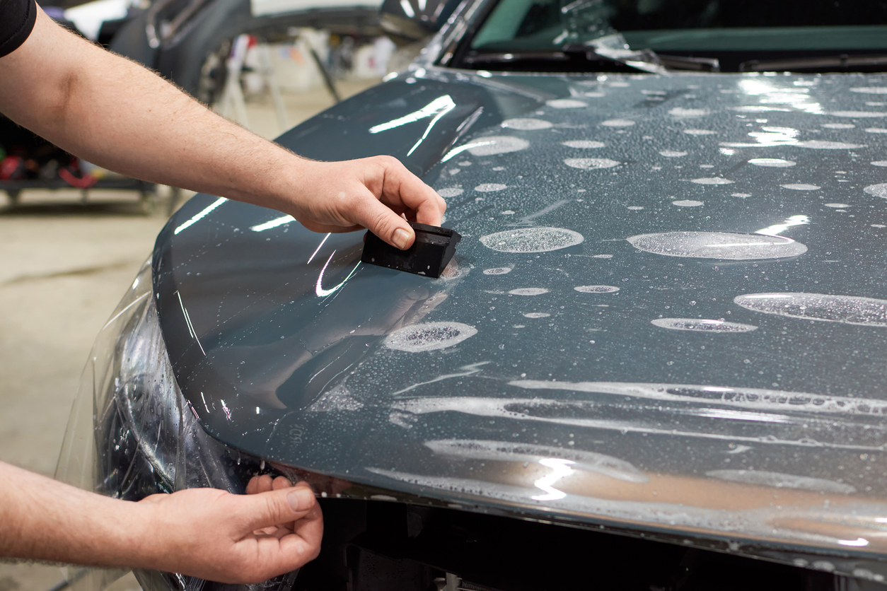 Installation of a protective paint and varnish transparent film on the car. PPF polyurethane film to protect the car paint from stones, marks and scratches.